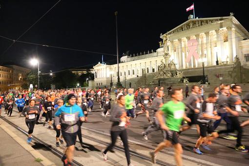 Runners running past the parliament at the Ring boulevard at night
