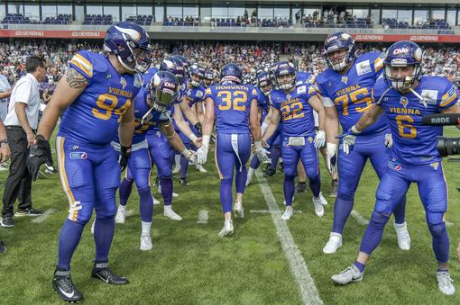 Photo of the Vienna Vikings "high-fiving" on the field, the players wear blue-orange jerseys