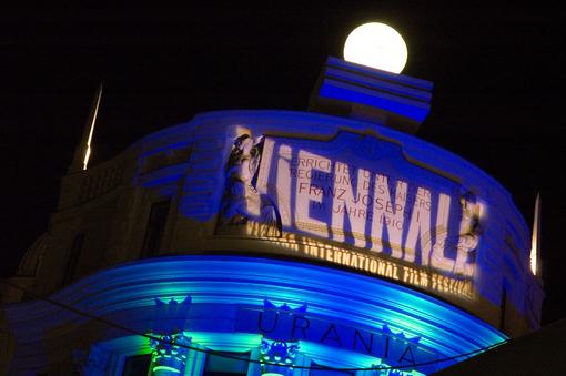 Photo of the dome of the Urania at night, the dome is bathed in blue light and the logo of the Viennale is projected on it