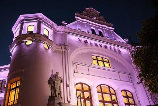 Volksoper mit neuer Fassade und magenterfarbener LED-Außenbeleuchtung in der Nacht