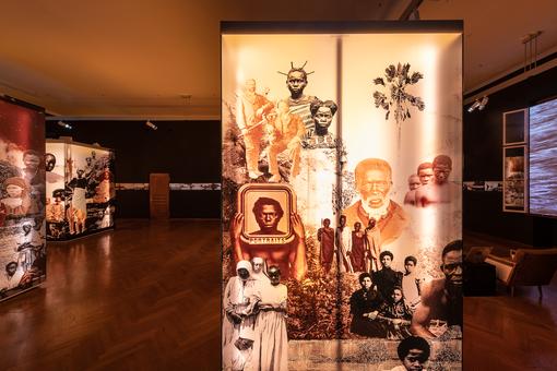 Ausstellungsansicht mit von hinten beleuchteten Bildern verschiedener indigener Völker
