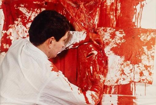Photo from 1963 showing Hermann Nitsch disemboweling an animal. You can see a lot of blood on white background
