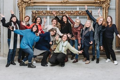 Group photo of the exhibition curators in front of two oversized, golden, baroque picture frames.