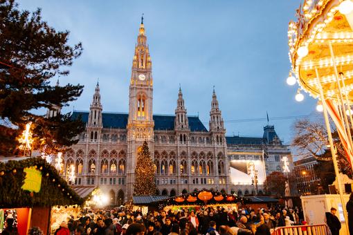 The photo shows the colorful hustle and bustle at the Vienna Christmas Market on Rathausplatz, the illuminated huts, Vienna City Hall in the background