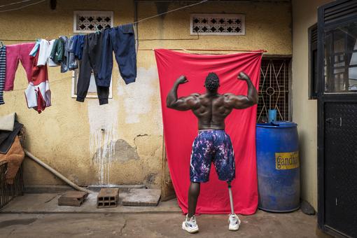 Der Bodybuilder Tamale Safalu trainiert vor seinem Haus. Kampala, Uganda. Er hat vom rechten Knie abwärts eine Metall-Protese