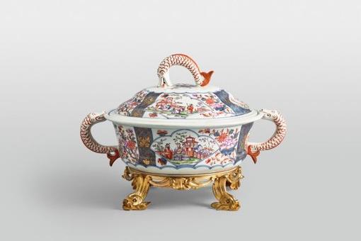 On display is a lidded tureen made of the finest porcelain with Chinese motifs, fish handles and golden fish legs