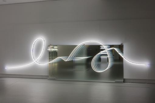 The photo shows the light installation by Brigitte Kowanz Email 02.08.1984 03.08.1984, a neon light carving in front of a mirror at the bottom of a wall