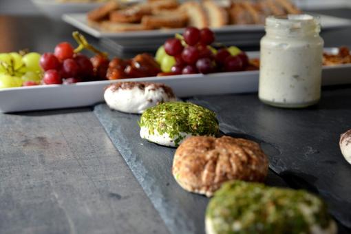 The photo shows four cream cheese variations in the form of small patties sprinkled with different spice mixtures, arranged on a slate plate.