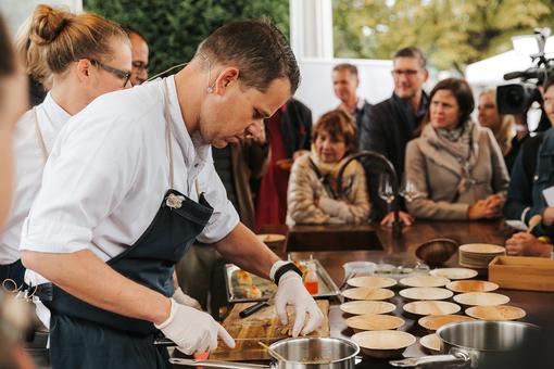 Das Foto zeigt den Koch des Jahres 2022 Max Natmessnig bei einem Schaukoochen vor Publikum bei der Gault & Millau Genuss-Messe 2024