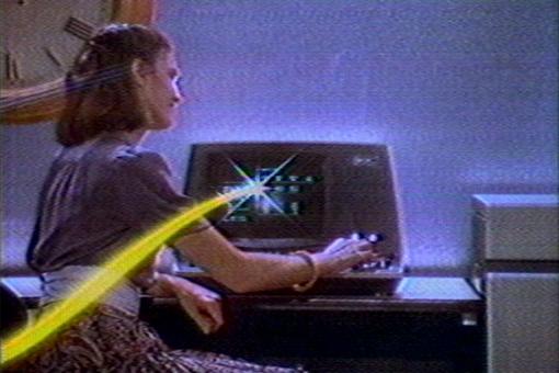 Das Foto aus den 1980er Jahren zeigt eine Frau vor einem Computer aus dieser Zeit