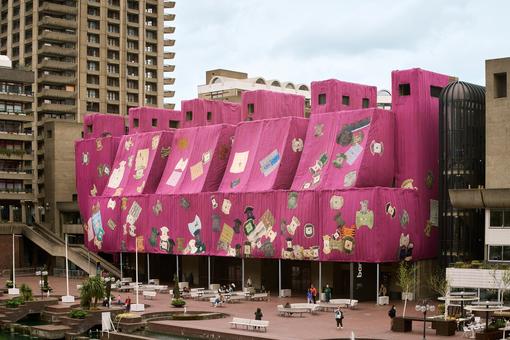 Das Foto zeigt die Verhüllung des Barbican Centre in London 2024. Die Verhüllung "Purple Hibiscus" wurde kreiert vom Künstler Ibrahim Mahama aus Ghana.