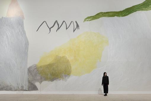 Das Foto zeigt die Künstlerin Jongsuk Yoon vor dem überdimensional großen (Wand)Gemälde "Sun and Moon"
