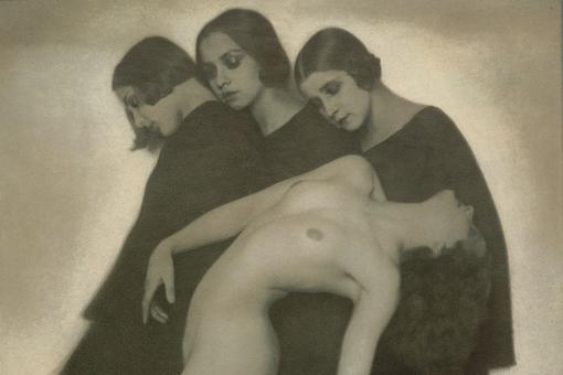 Black and white print showing three women in black dresses with bobbed heads and closed eyes leaning against each other. In front of them a naked woman bent over backwards.