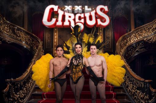 Veranstaltungsplakat zu "Circus XXL Pride Editon - Yes, we can can!", Dragqueen Tamara Mascara in Varietè-Kostüm mit großen gelben Straussenfedern, flankiert von zwei jungen Männern in schwarzen Underpants
