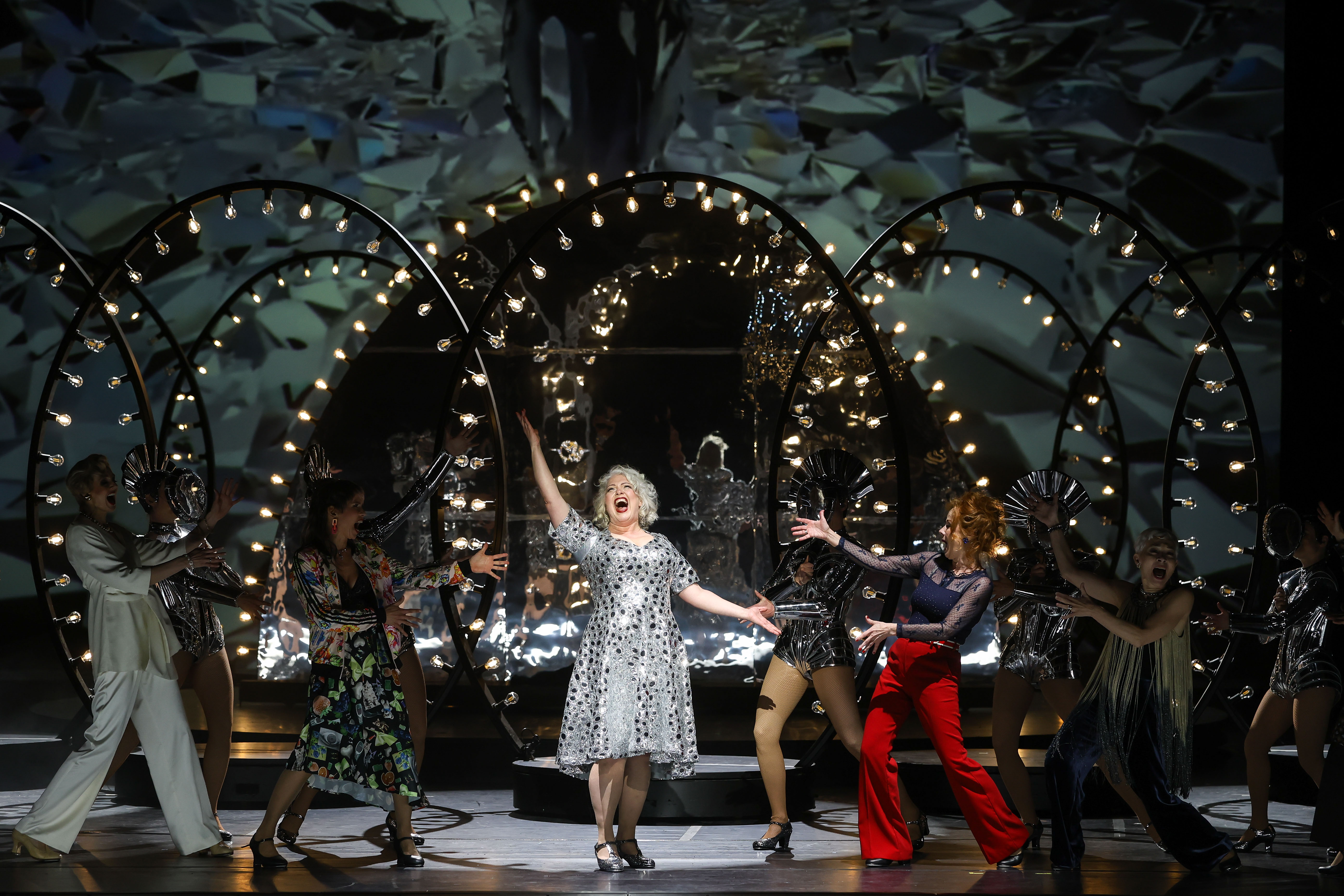Musical Follies / Ensemble - © Barbara Pálffy / Volksoper Wien Scene photo of the musical “Follies” at the Volksoper Vienna, in the center one of the leading actresses in a silver dress with black polka dots, surrounded by members of the ensemble