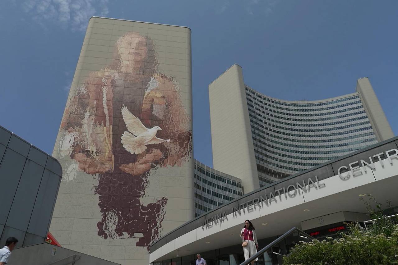 The United Nations in Wien @ Street Art von Fintan Magee in Zusammenarbeit mit Calle Libre The photo shows the UNO-City - Vienna International Center in Vienna with a street art painting / mural showing a woman from whose hand a dove of peace flies away