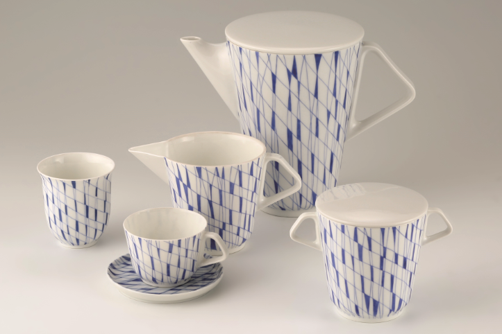 The photo shows a porcelain mocha service in white and blue diamond pattern with coffee pot, mocha cup with saucer, sugar bowl, milk jug and mug