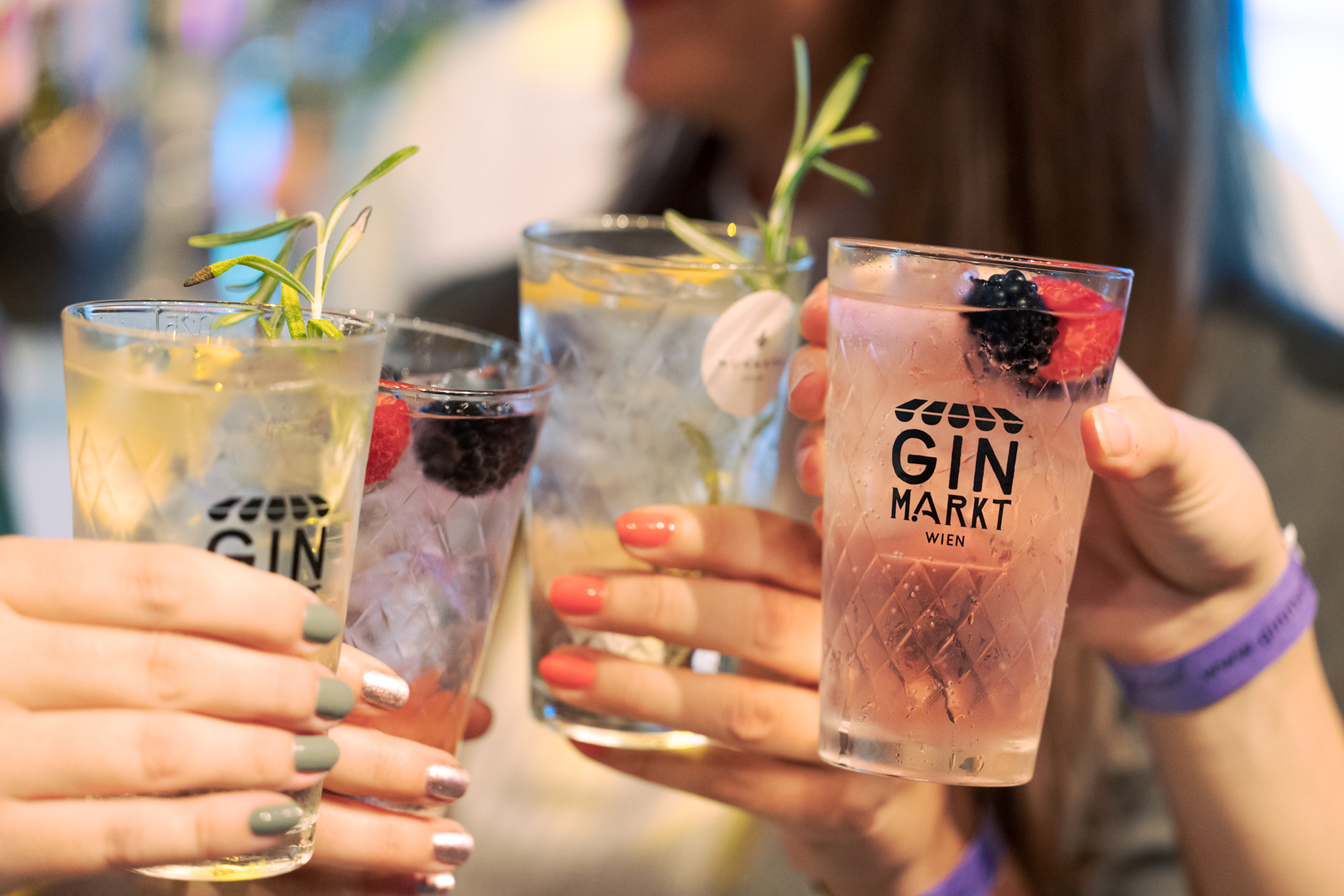 Ginmarkt @ Alexander Felten Photo of four hands with different nail polish, all holding gin glasses with the logo of the gin market and gin cocktails