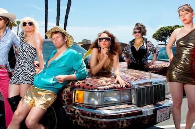 Johann Strauss 2025: Turn © Garrett Davis Das Foto zeigt vier Frauen und zwei Männer in auffallenden Outfits um ein Luxusauto in Leopardenlook lackiert