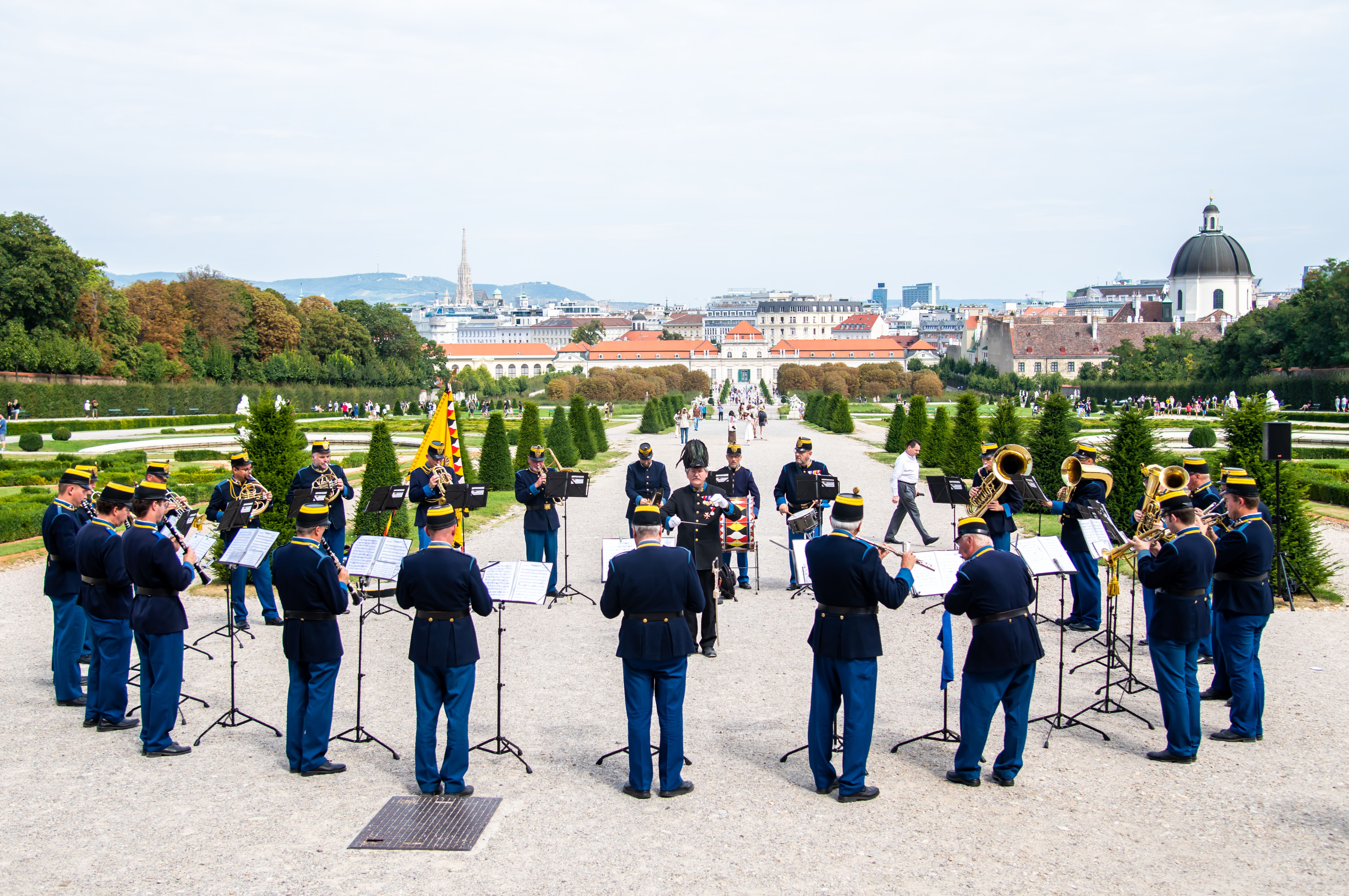 Original Hoch- und Deutschmeister © Foto: Harald Schuster Das Foto zeigt die traditionelle Blasmusik-Kapelle der Original Hoch- und Deutschmeister im Schlosspark Belvedere vor dem Oberen Belvedere mit Blick auf den Park, auf das Untere Belvedere. Die Musiker tragen traditionelle dunkelblaue Uniformen.