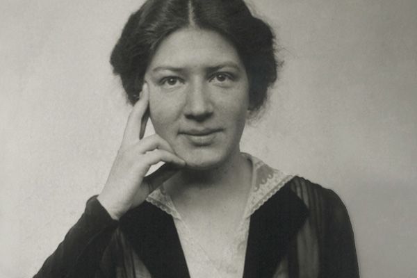 © Leichter Family Archive Zu sehen ist ein Porträtfoto in schwarzweiß von Käthe Leichter. Sie trägt ihr dunkeles Haar hochgesteckt, trägt ein elegantes Oberteil mit weißem Spitzenkragen