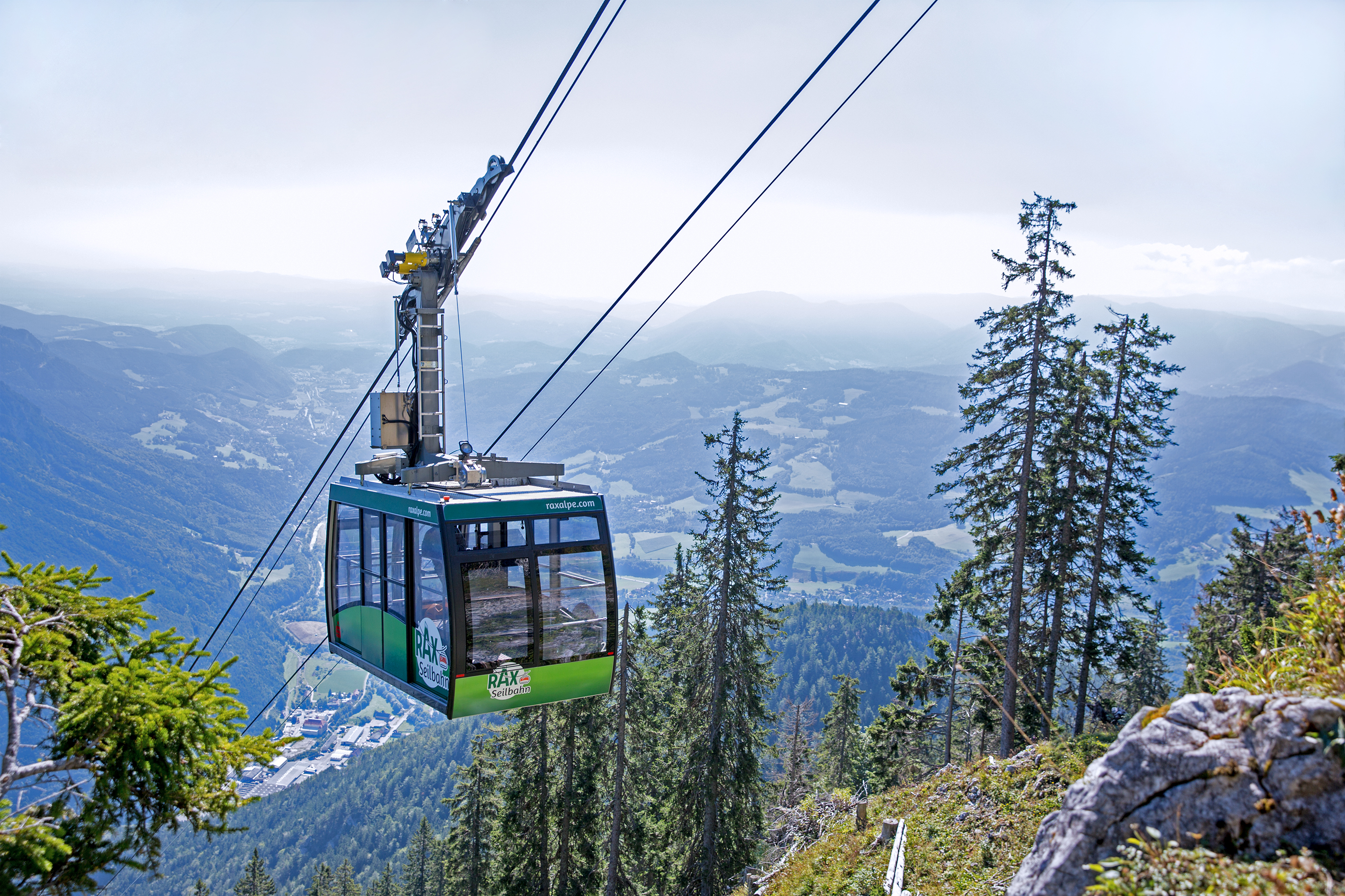 Rax-Seilbahn © Katrin Nusterer Photo of a green cable car gondola, in the background the landscape of the Vienna Alps
