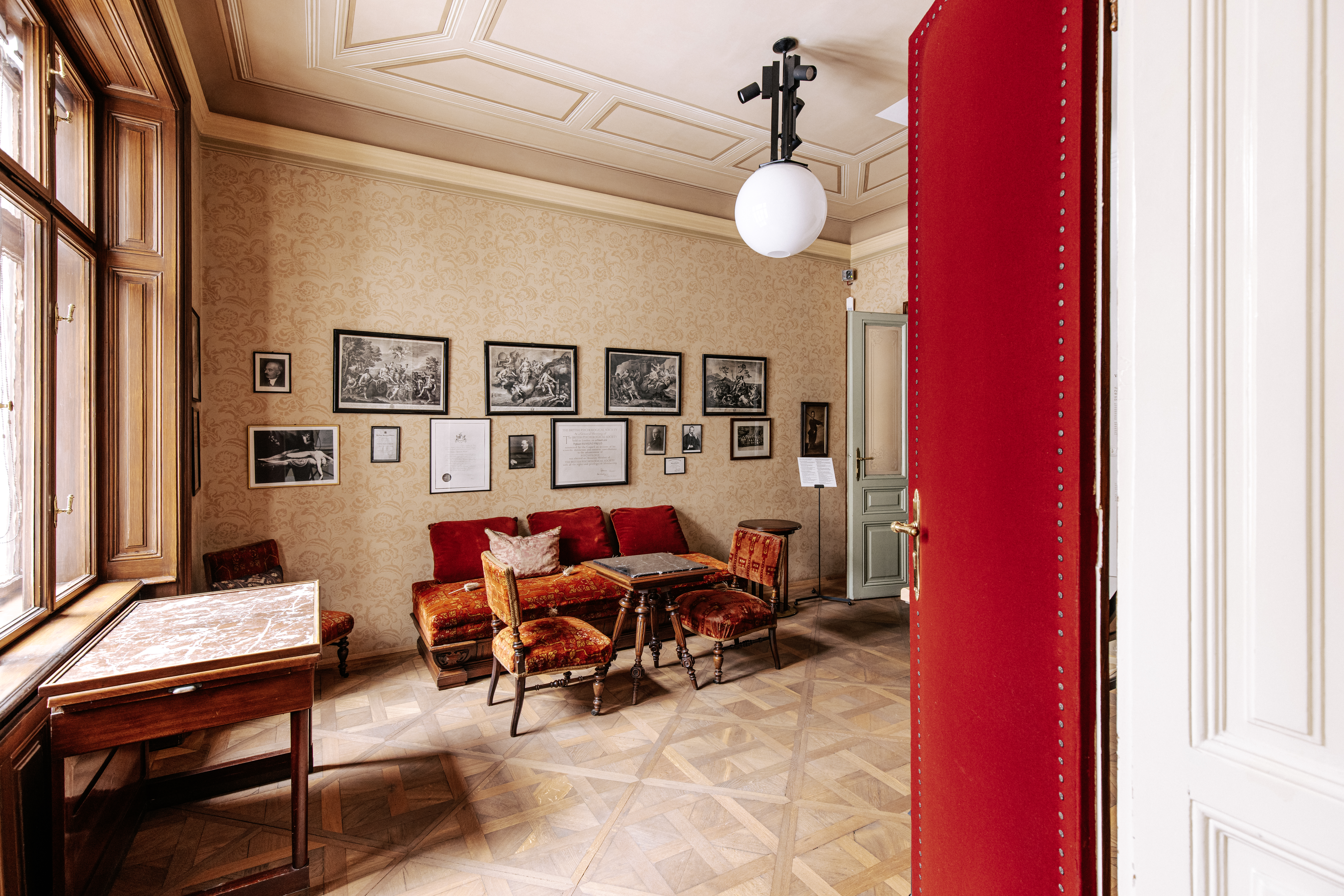 © Foto: WienTourismus / Paul Bauer Photo of a room with sofa, table and two chairs, pictures on the wall, open double doors, box window