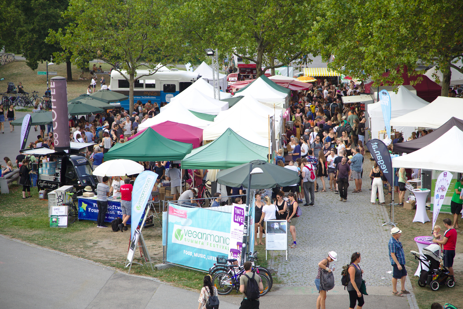 Foto: © Veganmania 2021 Foto mit Ständen und vielen Menschen, die zwischen den Ständen und Pavillons flanieren